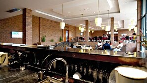 A modern restaurant with a brick wall, a bar area, and a seating area with tables and chairs. - BENGO HOTEL (Ebolowa)