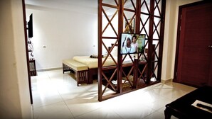A room with a bed, a TV, and a wooden partition. - BENGO HOTEL (Ebolowa)