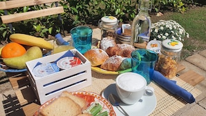 Una mesa al aire libre con frutas, pasteles y bebidas para un picnic.