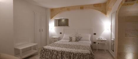 A bedroom with a large bed, a nightstand, a dresser, and a small table.
