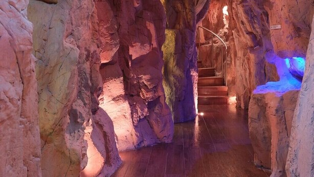 A cave-like interior with a wooden staircase leading to a higher level. - PlazaCarrisi Hotel & Spa (Cellino San Marco)