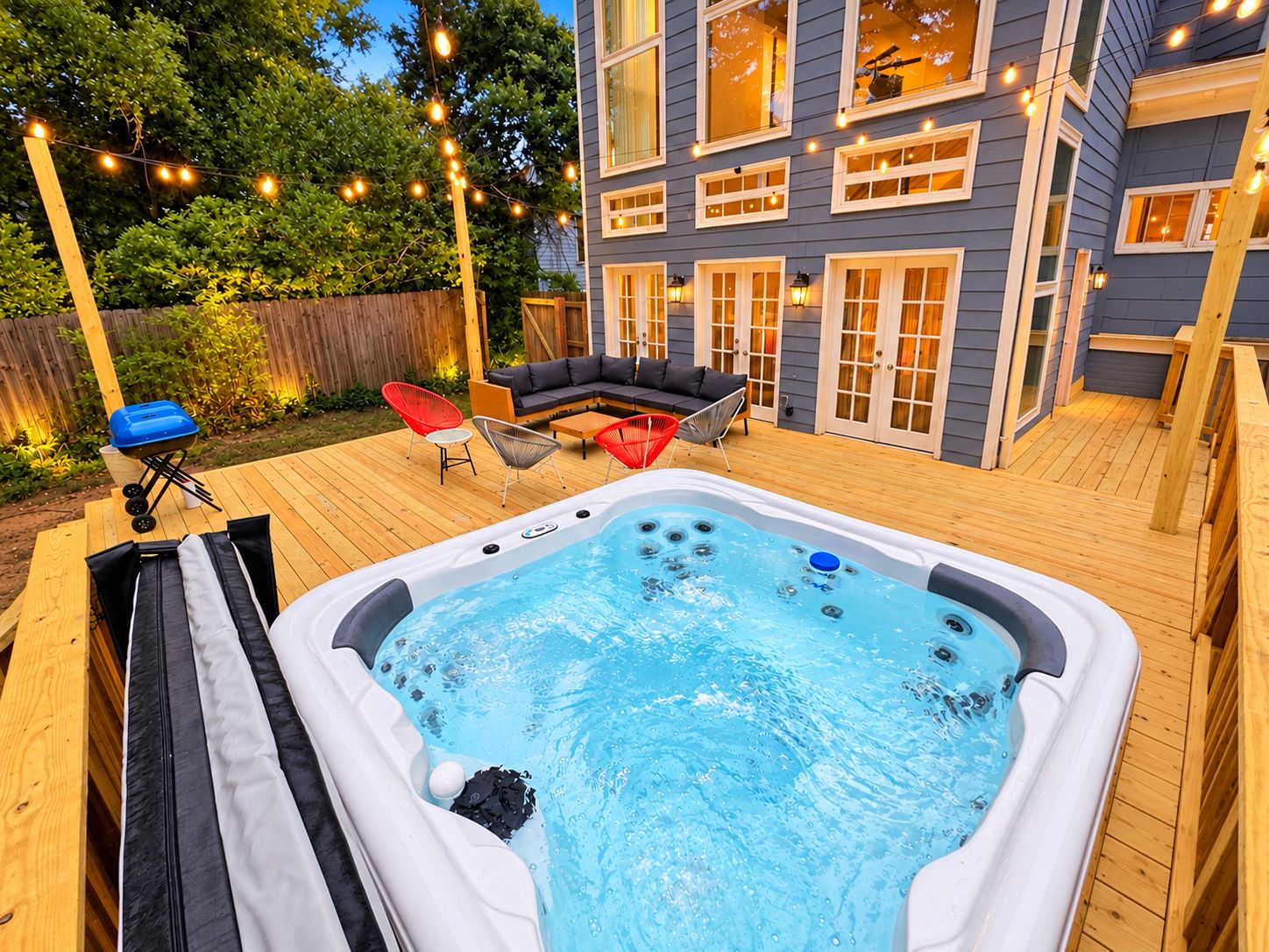 Ein Garten mit Whirlpool, Gartenmöbeln und Lichterketten.
