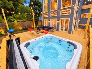 En baghave med jacuzzi, udendørs møbler og lyskæder.