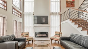 Un salón amplio con chimenea, sofás de cuero y una escalera.