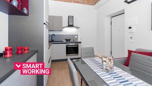 A compact kitchen with modern appliances, a dining area with a table and chairs, and a small seating area with a sofa. - Loft del Conte nei pressi della Mole by Wonderful Italy (Torino)