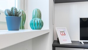 A desk with a computer monitor, a framed welcome sign, and two potted plants. - Loft del Conte nei pressi della Mole by Wonderful Italy (Torino)