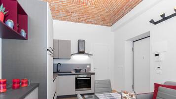 Eine kompakte Küche mit modernen Geräten, ein Essbereich mit Tisch und Stühlen sowie eine kleine Sitzecke mit einer Couch.