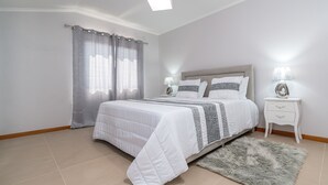 A bedroom with a bed, curtains, a nightstand, and a rug.
