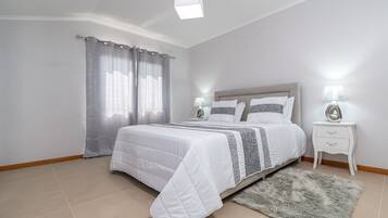 Un dormitorio con cama, cortinas, mesita de noche y alfombra.