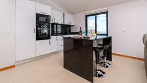 A modern kitchen with white cabinets, a black island, and a large window.