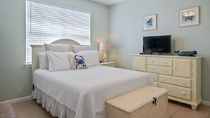 Ein Schlafzimmer mit Bett, Fernseher, Kommode und einer Bank.
