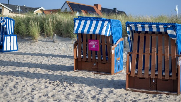 Beach chairs with striped canopies and a sign indicating a family-friendly area.
