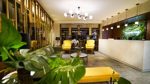 A hotel lobby with a reception desk, two yellow armchairs, a green sofa, and a marble coffee table. - Fragments Hotel (Istanbul)