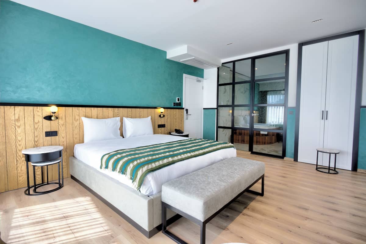 Un dormitorio moderno con una cama grande, cabecero de madera, mesitas de noche y un banco.