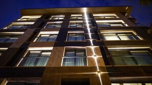 A multi-story building with a modern architectural design, featuring a grid of windows and illuminated entryways. - Fragments Hotel (Istanbul)