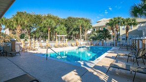 Relax by the pool surrounded by lush greenery and comfortable lounge chairs.