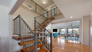 A spacious living area with a wooden staircase and a high ceiling. - Horseshoe Bay - Lakefront + Pool - Lucy on the Lake (Horseshoe Bay)