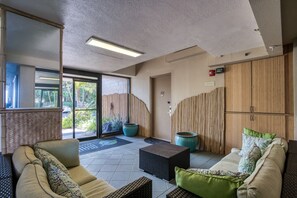 A modern hotel lobby with a seating area, a reception desk, and a view of the outdoors.