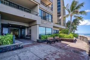 A hotel with a balcony, outdoor seating, and a view of the ocean.