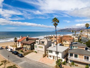 A coastal residential area with houses, a beach, and a clear sky.