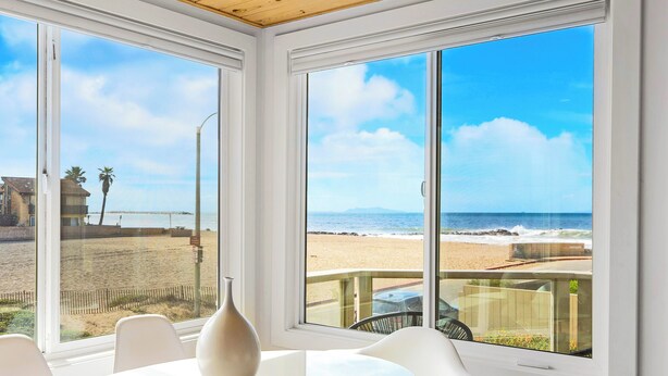 Een kamer met grote ramen, met uitzicht op het strand en de oceaan.