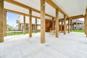 Ein geräumiger Innenbereich mit freiliegenden Holzbalken und einem Betonboden, mit einer Treppe und einem Picknicktisch.