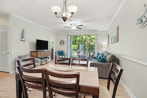 A dining area with a table, chairs, a ceiling fan, and a view of the outdoors.