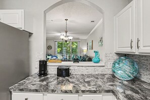 A kitchen with a marble countertop, a toaster, a coffee maker, and a decorative blue vase.