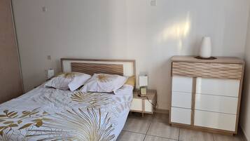 A neatly arranged bedroom with a bed, bedside tables, a nightstand, and a wardrobe.