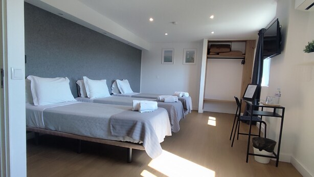 A hotel room with three beds, a desk, a chair, and a television mounted on the wall. - Residencial Douro (Peso da Régua)