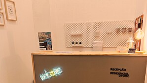 A reception desk with a neon sign, a framed picture, and a wall-mounted light fixture. - Residencial Douro (Peso da Régua)