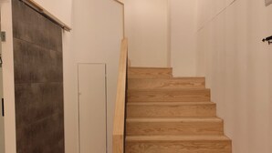 A modern staircase with wooden steps and a dark sliding door. - Residencial Douro (Peso da Régua)