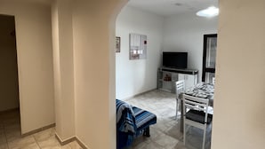 A spacious living area with a tiled floor, a dining table with chairs, a sofa, and a television. - VILLA MACCIONI 2  (Tanaunella)