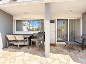 An outdoor patio with a table and chairs, a door, and a view of a building. - Rêves salés Appartement une chambre 4 couchages avec terrasse 17m2 plage (Le Grau-du-Roi)