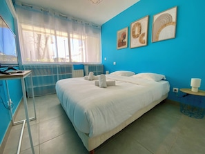 Habitación de hotel con cama, escritorio, silla y ventana con cortinas.