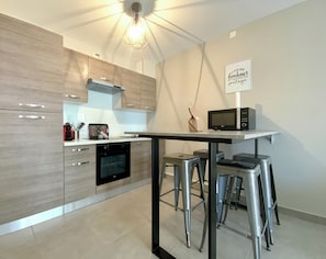 Una cocina moderna con horno empotrado, microondas y una zona de taburetes de bar.