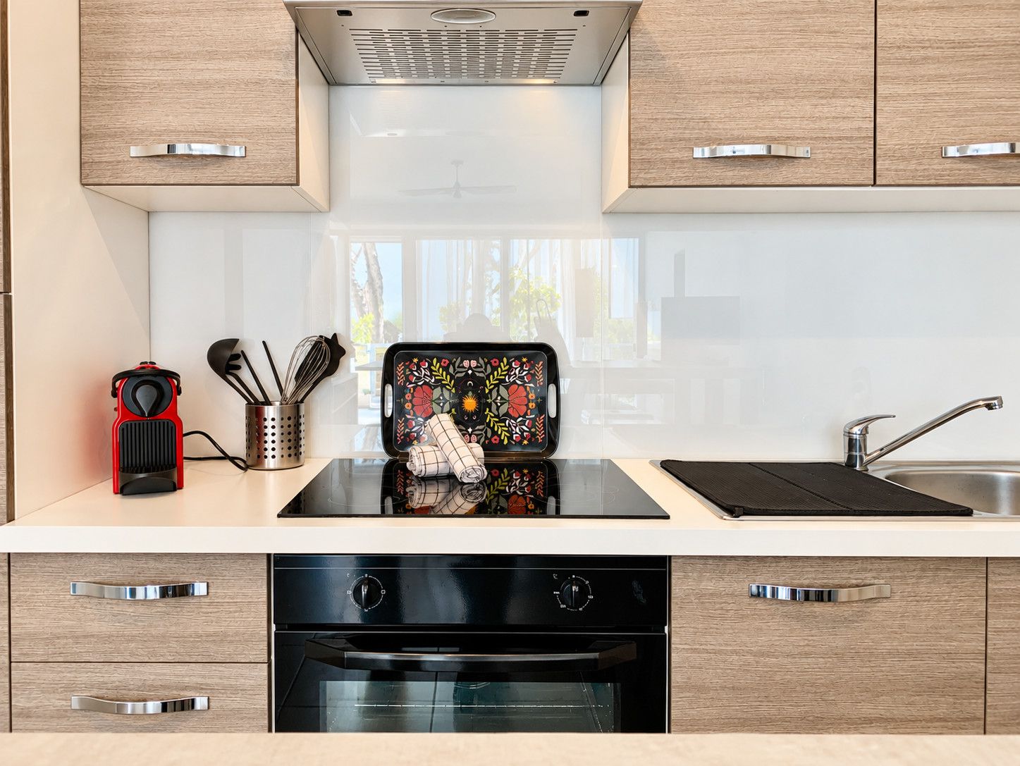 Una cocina moderna con horno empotrado, pileta de acero inoxidable y muebles de madera.