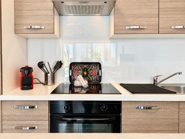 A modern kitchen with a built-in oven, a stainless steel sink, and wooden cabinets.