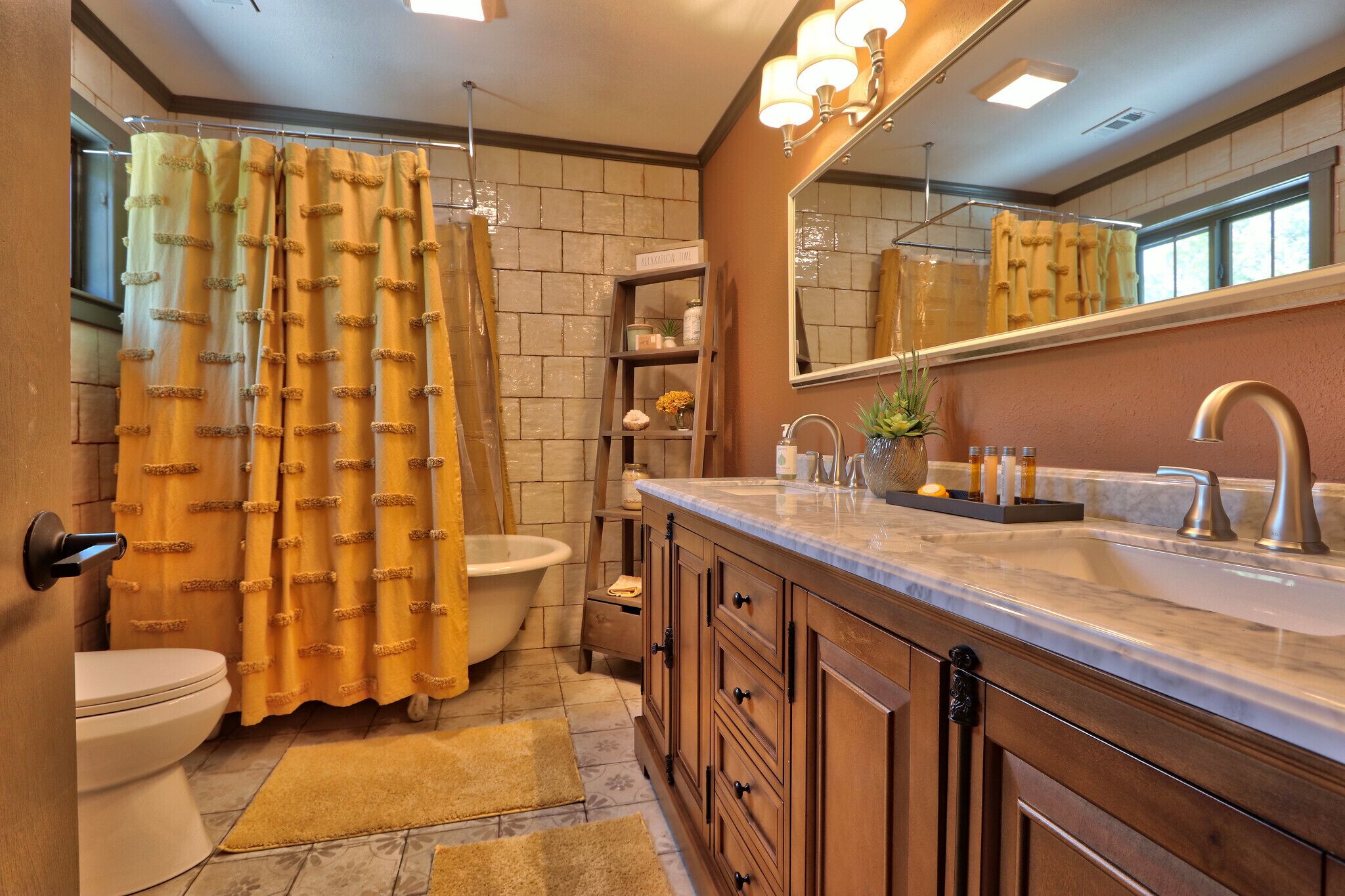 A bathroom with a bathtub, toilet, vanity with a sink, and a mirror.