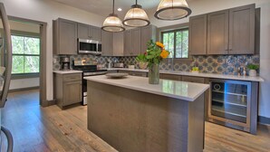 A modern kitchen with a central island, stainless steel appliances, and pendant lighting.