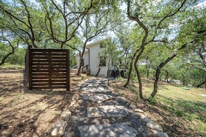 A stone pathway leading to a white building surrounded by trees.