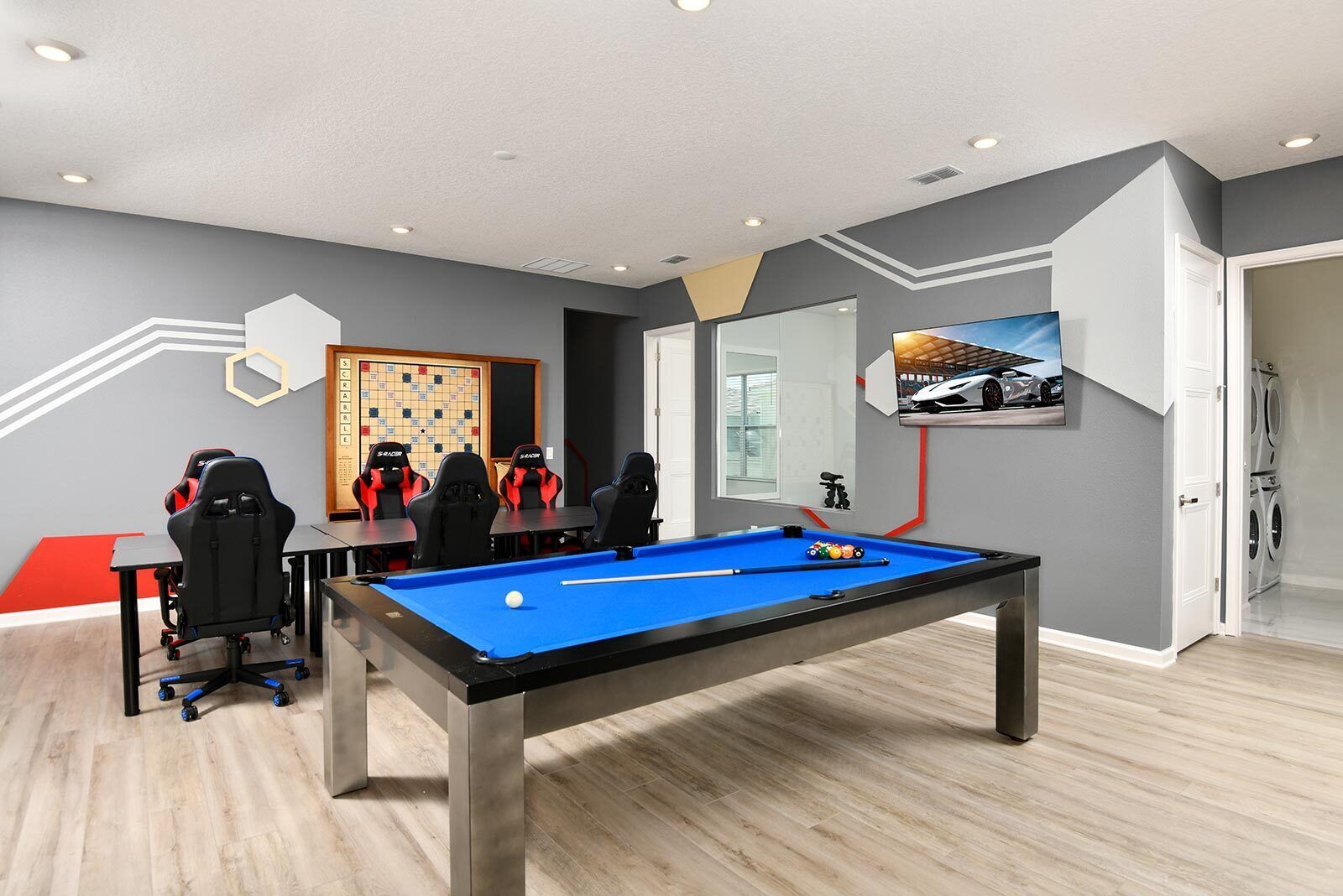 Een moderne kamer met een pooltafel, game stoelen, een schaakbord en een auto-thema kunstwerk.