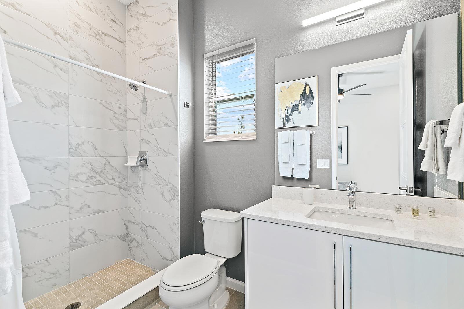 Een moderne badkamer met douche, toilet en wastafel.