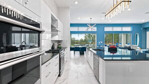 A modern kitchen with a large island, stainless steel appliances, and a view of the outdoors. - Cozy Home w Treehouse RM, Bowling Arcade, Theater, Castle Theme BR, Near Disney (Davenport)