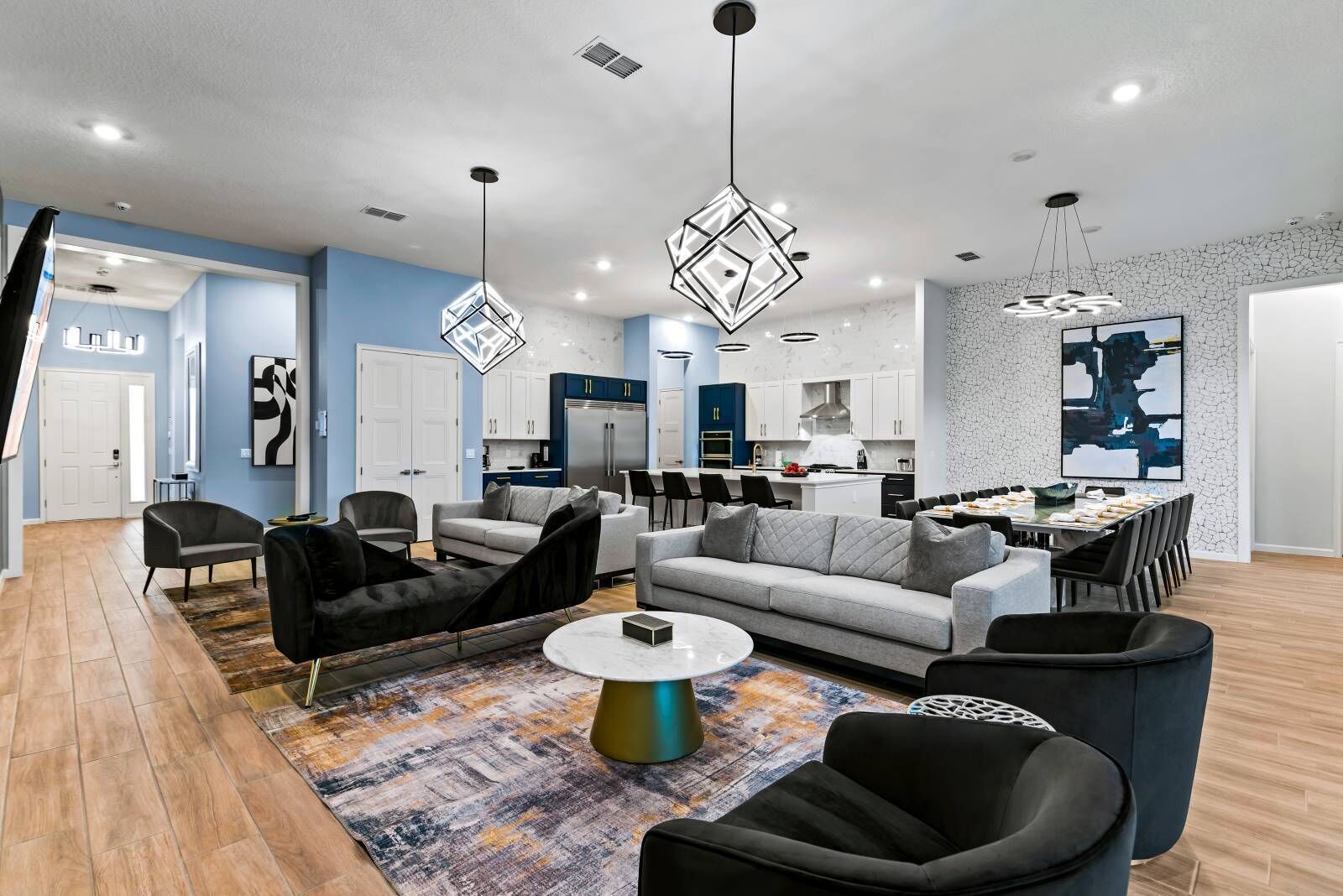 A modern living room with a sofa, chairs, a coffee table, and a kitchen area with a dining table.