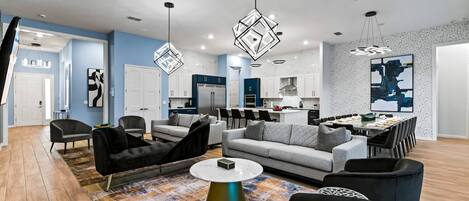 A modern living room with a sofa, chairs, a coffee table, and a kitchen area with a dining table.