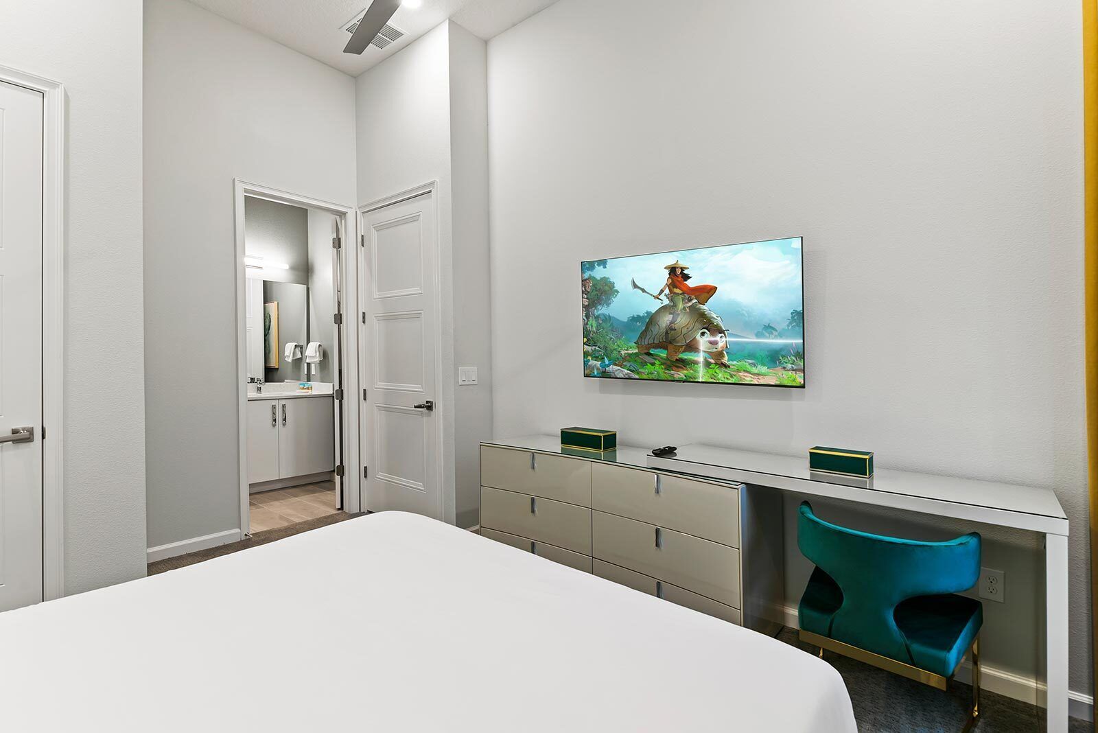 A modern bedroom with a large bed, a desk with a computer, and a chair.