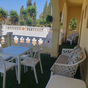An outdoor patio with a table and chairs, a sofa, and a decorative fence.