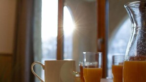 Un tavolo con una tazza e un piattino bianchi, un bicchiere di succo d'arancia e una caraffa di succo d'arancia.