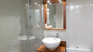 Un bagno moderno con box doccia in vetro, mobile bagno in legno, lavandino bianco e water.
